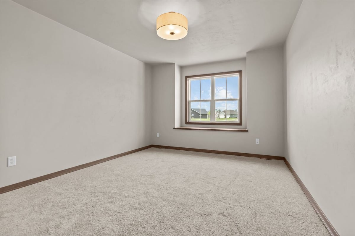 Bright carpeted bedroom with large window in a Northern Wisconsin home
