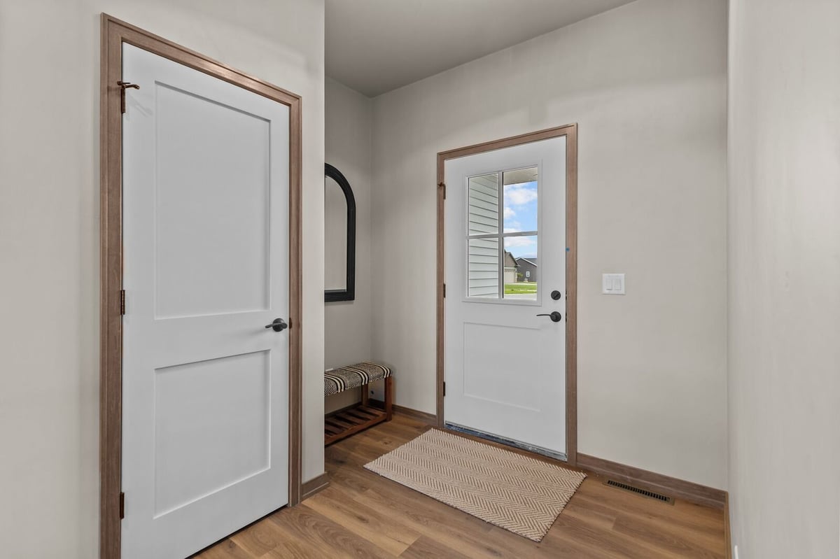 Bright mudroom entry with white door and wood floors in a Northern Wisconsin home