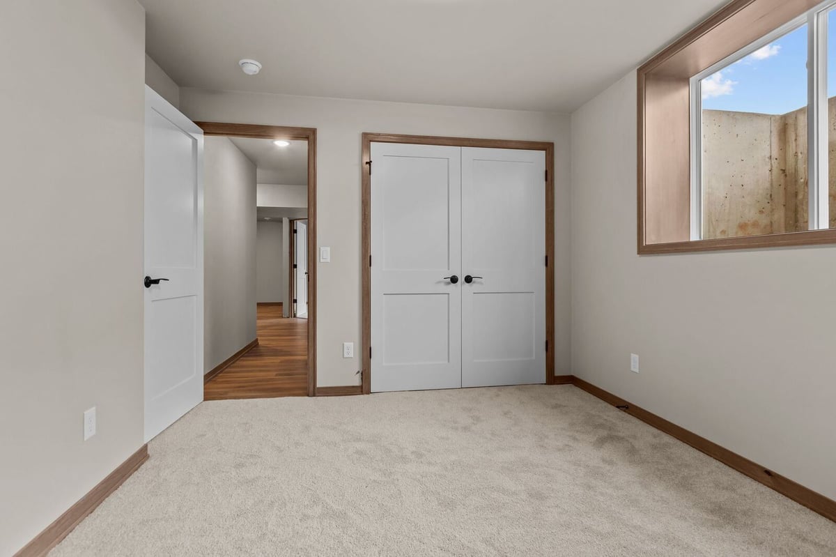 Carpeted bedroom with double closet doors and wood trim in a Northern Wisconsin home