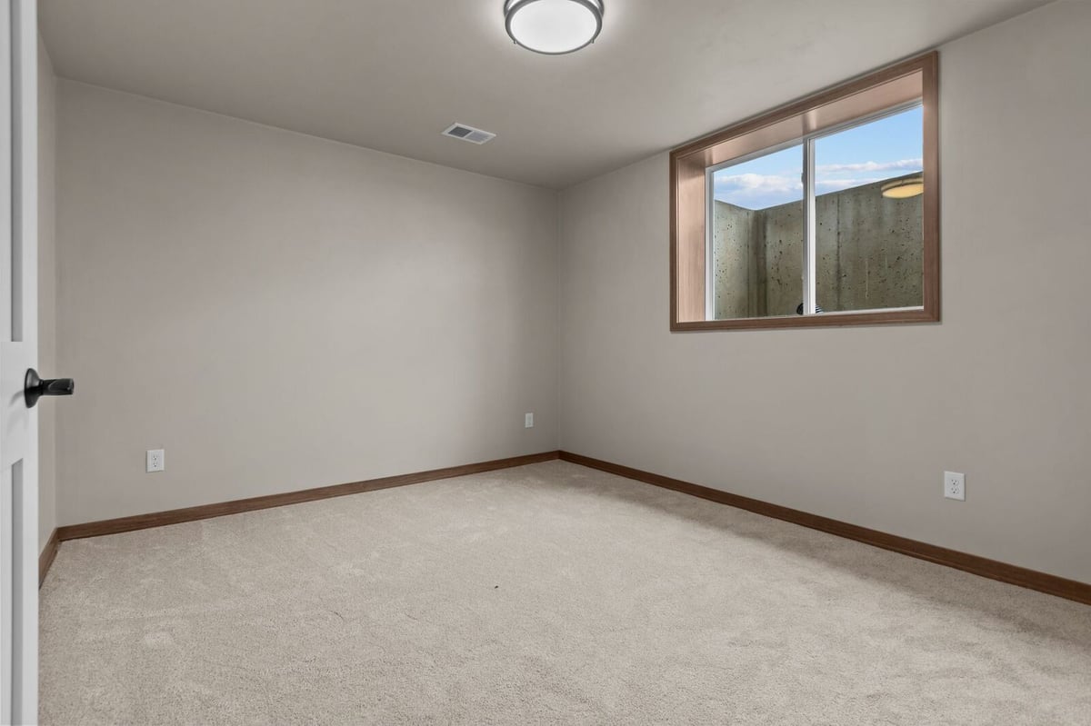 Carpeted lower-level bedroom with daylight window in a Northern Wisconsin home