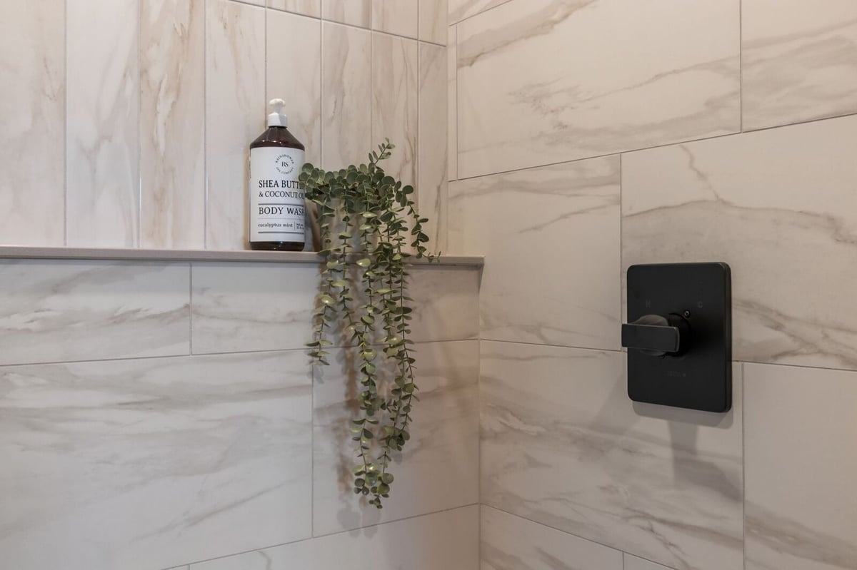 Close-up of tiled walk-in shower with matte black fixtures in a Northern Wisconsin home
