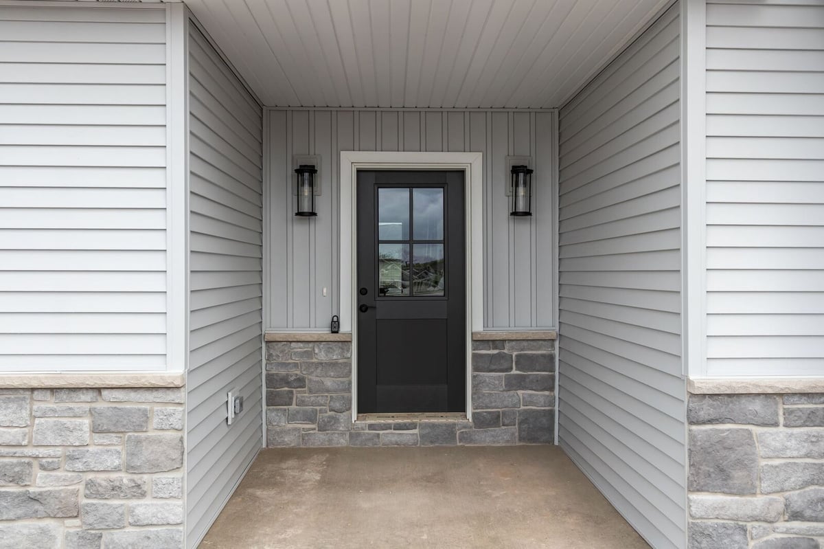 Covered front entry with black door and stone accents on a Northern Wisconsin home