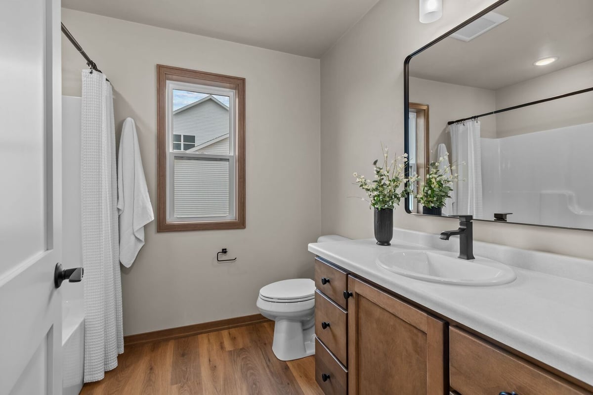 Modern bathroom with wood vanity and black fixtures in a Northern Wisconsin home