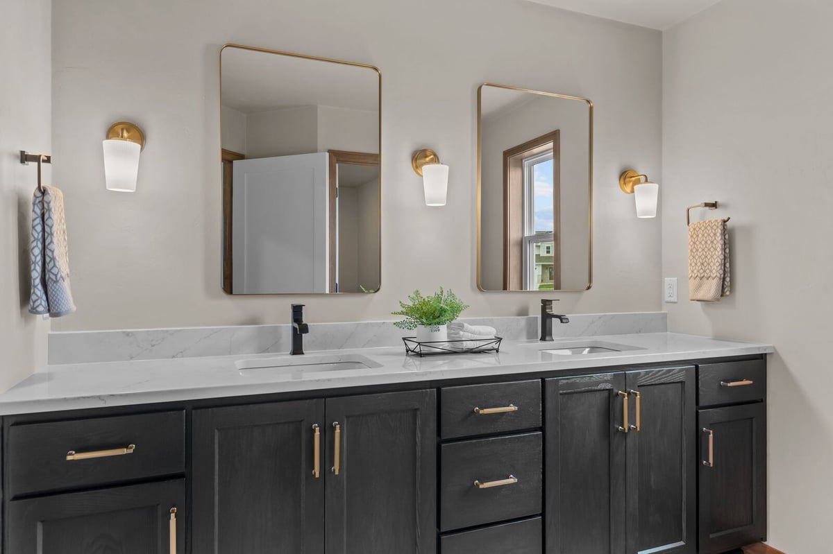Modern double vanity with gold mirrors and black cabinetry in a Northern Wisconsin bathroom