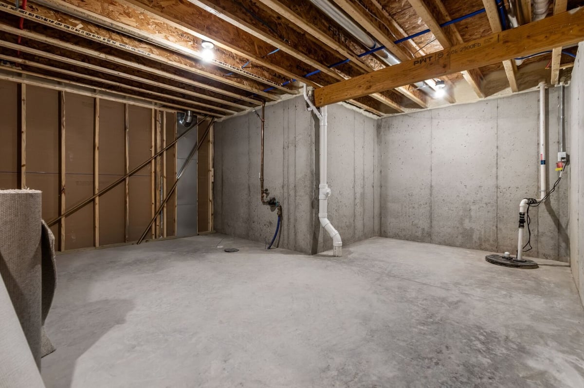 Open unfinished basement with concrete floors and exposed beams in a Northern Wisconsin home
