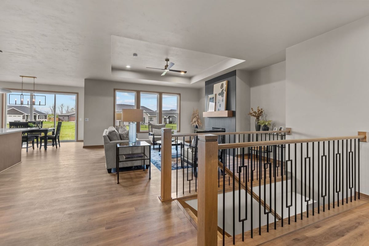 Open-concept living area with staircase railing and fireplace in a Northern Wisconsin custom home