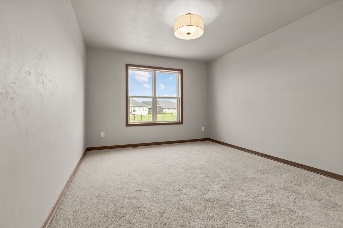 Spacious bedroom with plush carpet and natural light in a Northern Wisconsin home