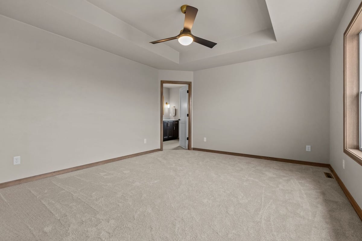 Spacious primary bedroom with tray ceiling and ensuite access in a Northern Wisconsin home