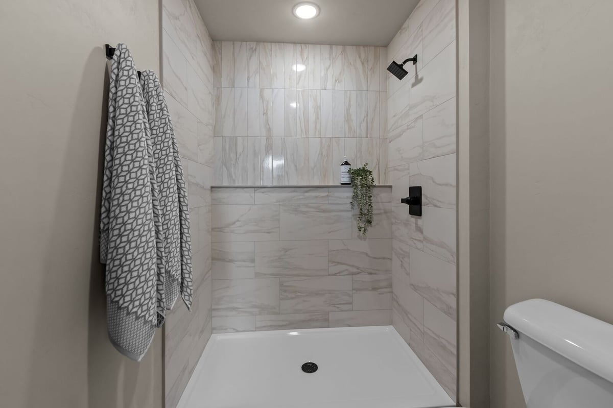 Tiled walk-in shower with built-in ledge and matte black fixtures in a Northern Wisconsin home