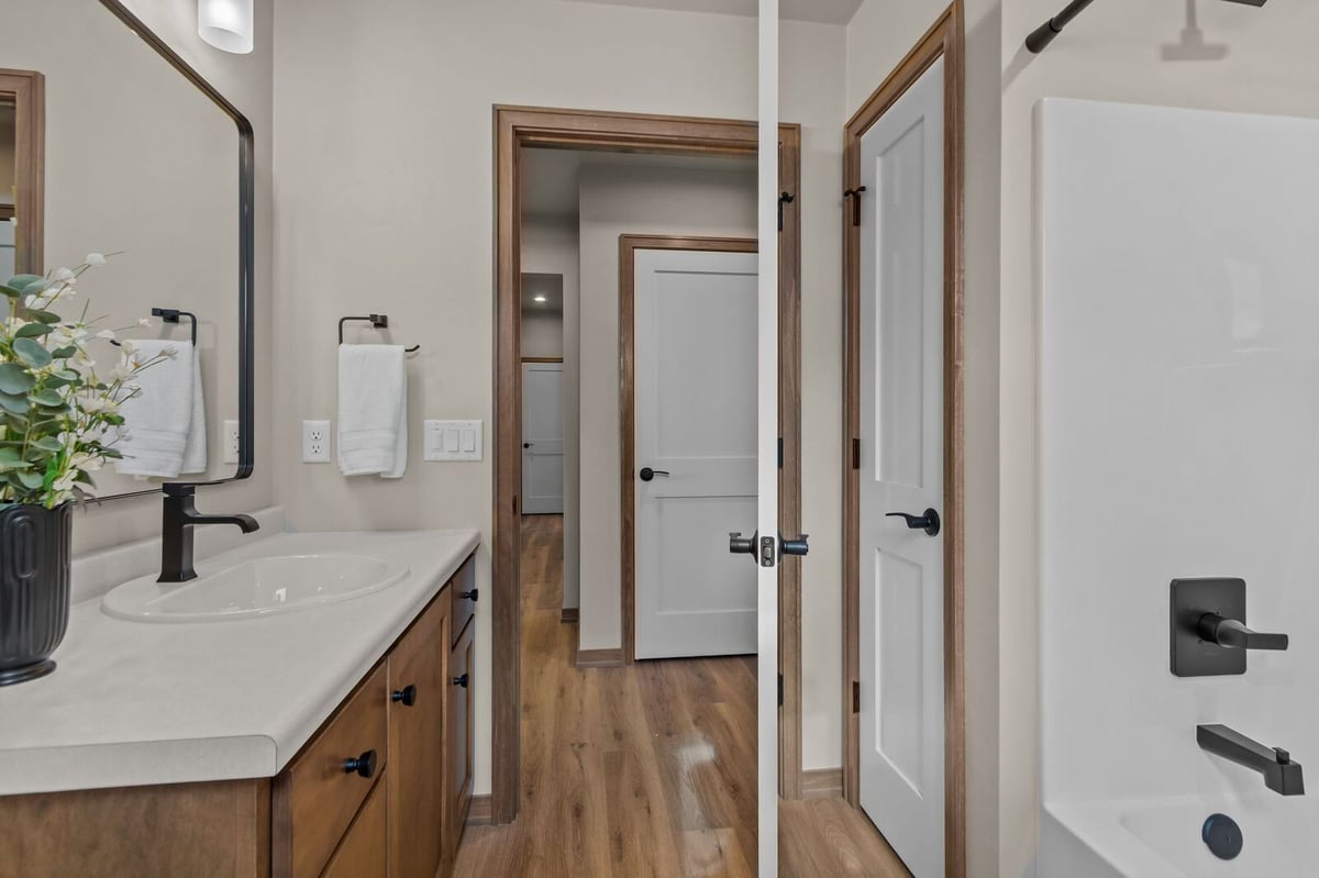 Tub shower and wood bathroom vanity with black fixtures in a Northern Wisconsin home
