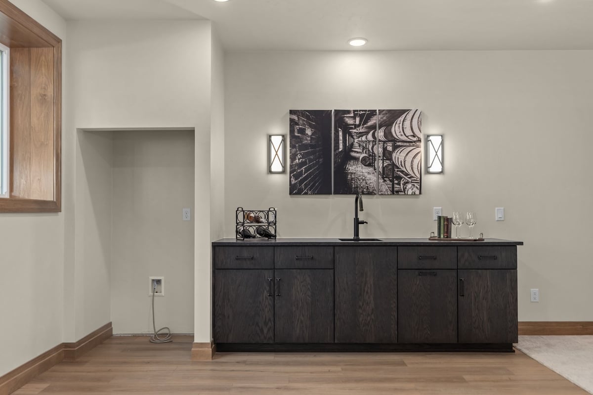 Basement wet bar with dark wood cabinetry, sink and wood flooring in a Northeast Wisconsin home