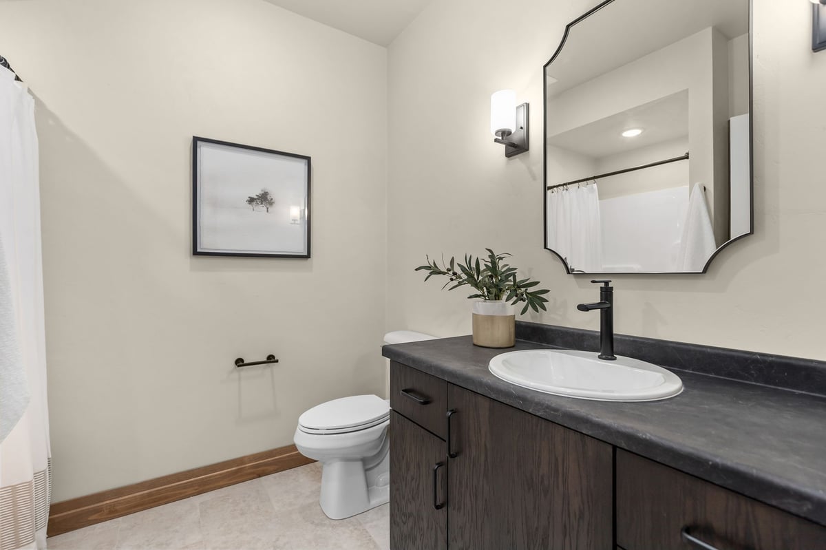 Bathroom with dark wood vanity, black fixtures and framed mirror in a Northeast Wisconsin home