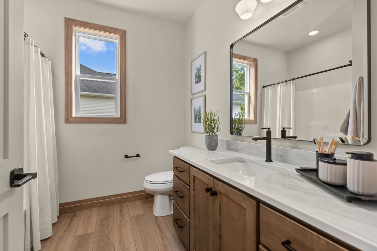 Bathroom with wood vanity, marble-look countertop and black fixtures in a Northeast Wisconsin home