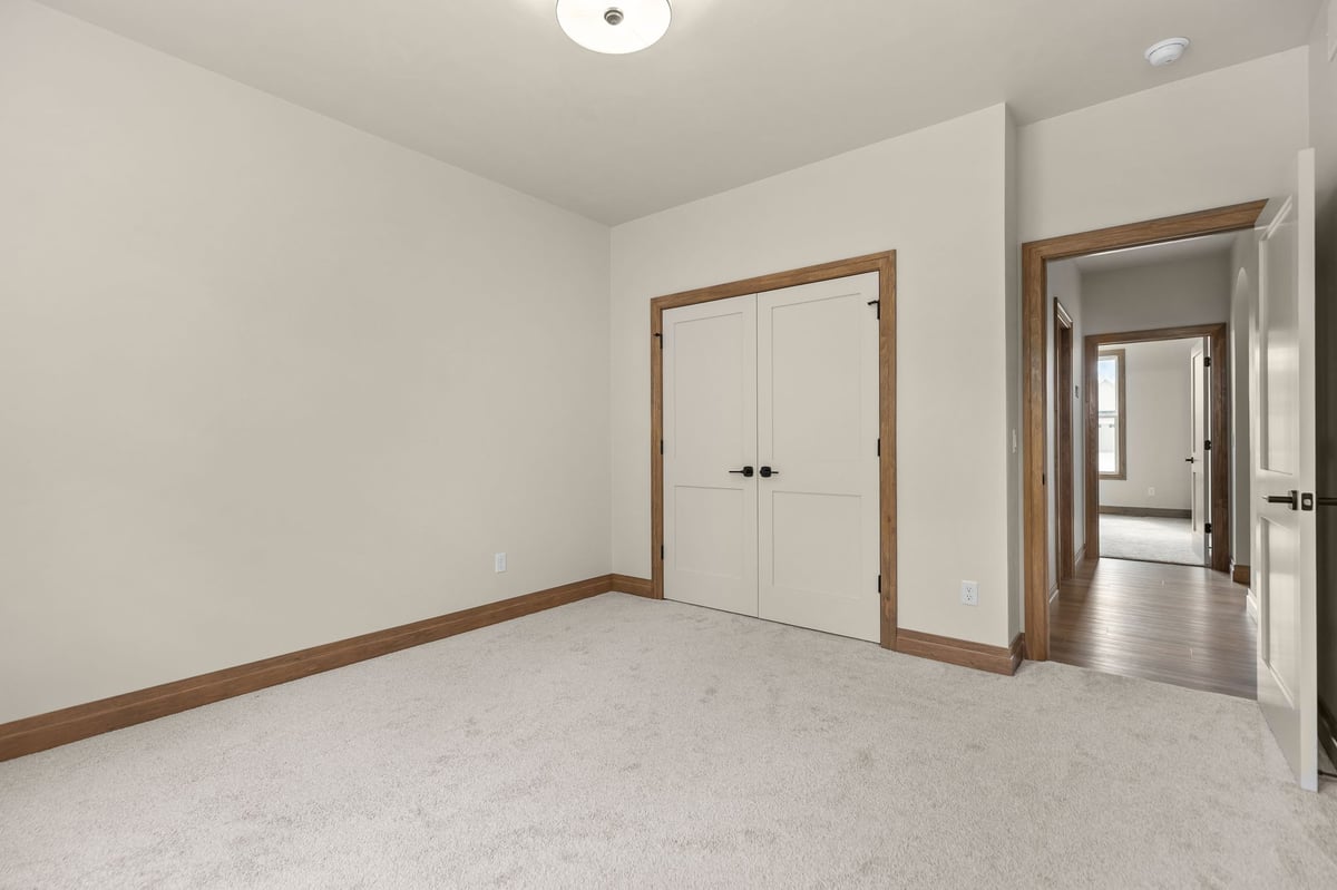 Carpeted bedroom with double closet doors and wood-trimmed entry in a Northeast Wisconsin home