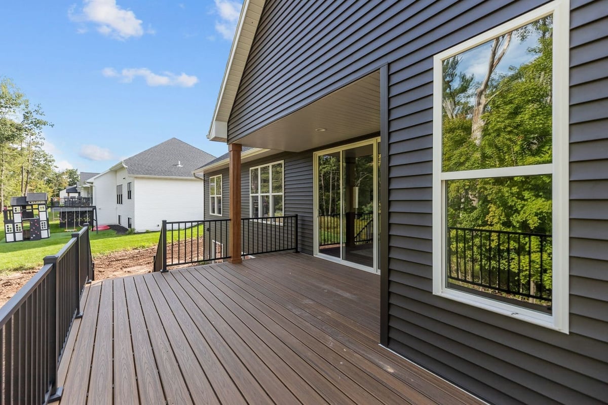 Covered composite deck with black railings overlooking a wooded backyard in Northeast Wisconsin