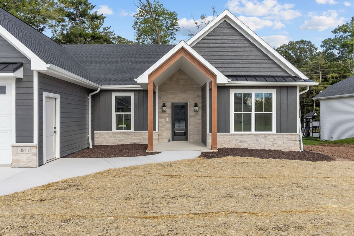 Covered front entry of a Northeast Wisconsin home with stone accents, wood posts and dark gray siding