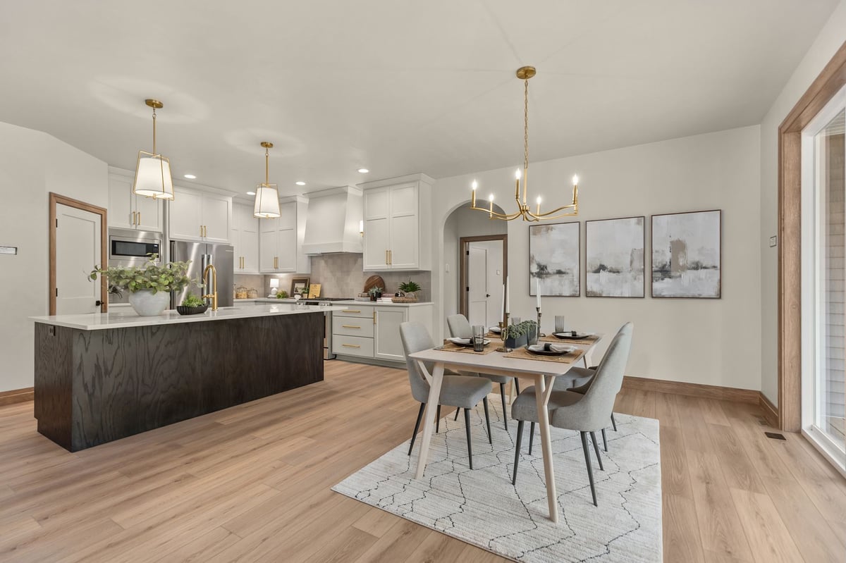 Dining area beside a modern kitchen with dark island and white cabinetry in a Northeast Wisconsin home