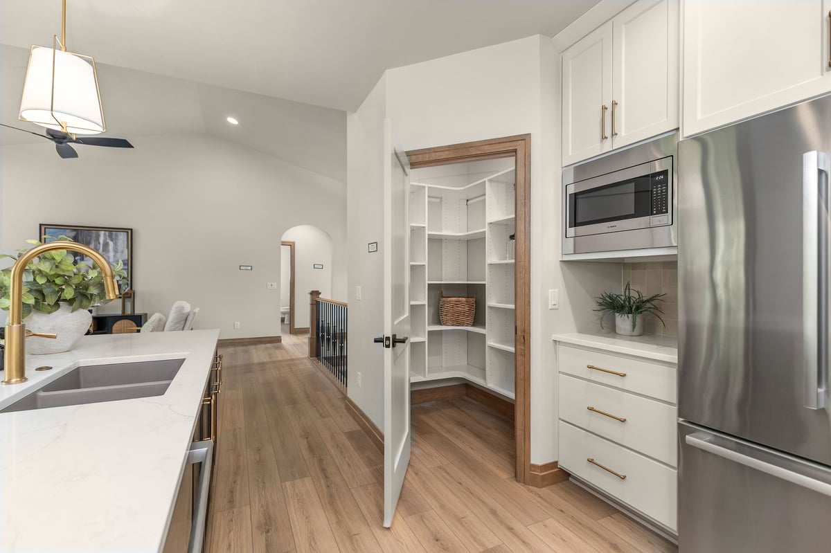 Kitchen pantry with built-in shelving beside stainless steel appliances in a Northeast Wisconsin home
