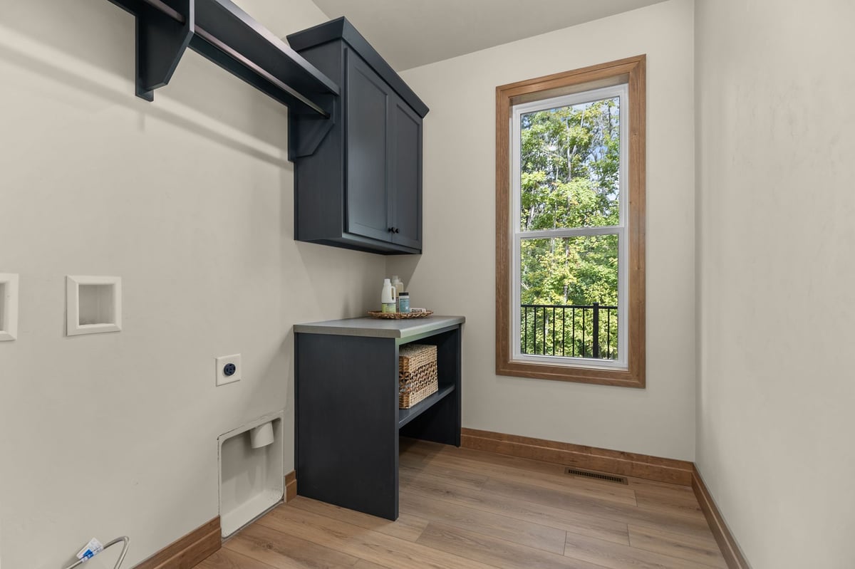 Laundry room with dark cabinetry, wood flooring and a large window in a Northeast Wisconsin home