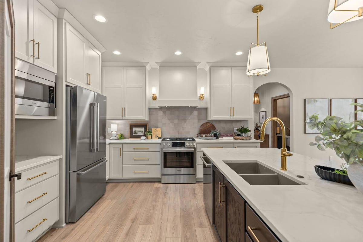 Modern kitchen with white cabinetry, dark island, quartz counters and brass accents in a Northeast Wisconsin home