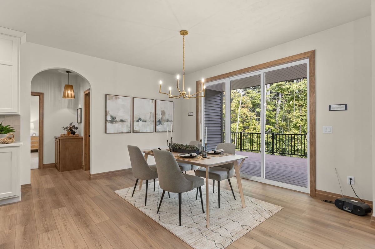 Northeast Wisconsin dining room with a wooded deck view, warm wood floors and modern brass chandelier