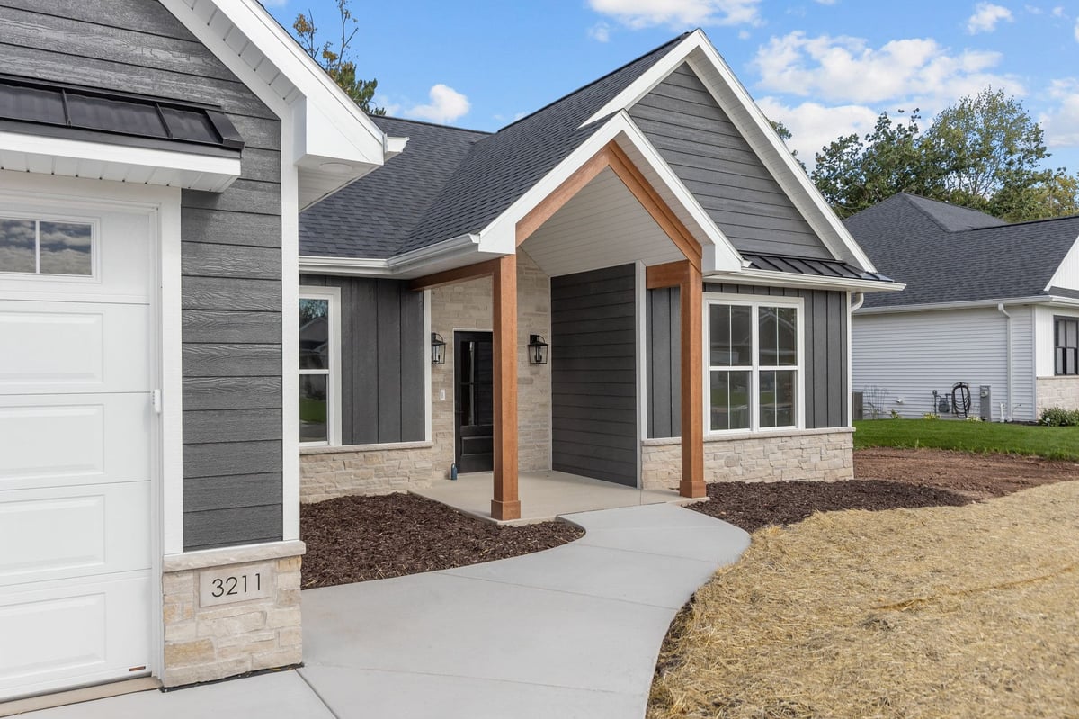 Northeast Wisconsin home exterior with dark siding, stone accents, wood posts and a covered front entry