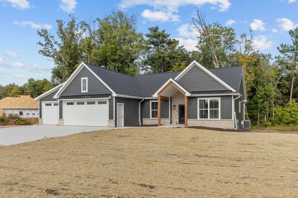 Northeast Wisconsin home with dark gray exterior, three-car garage and covered front entry