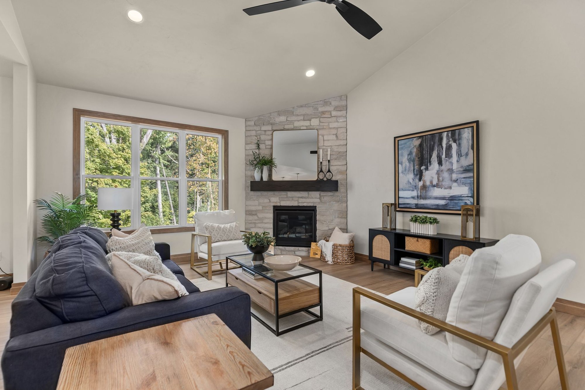 Northeast Wisconsin living room with stone fireplace, large wooded-view window and modern seating Northeast Wisconsin living room with stone fireplace, large wooded-view window and modern seating