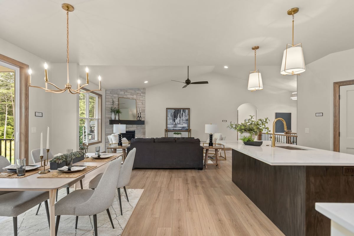 Open kitchen, dining and living area with wood-look flooring and stone fireplace in a Northeast Wisconsin home