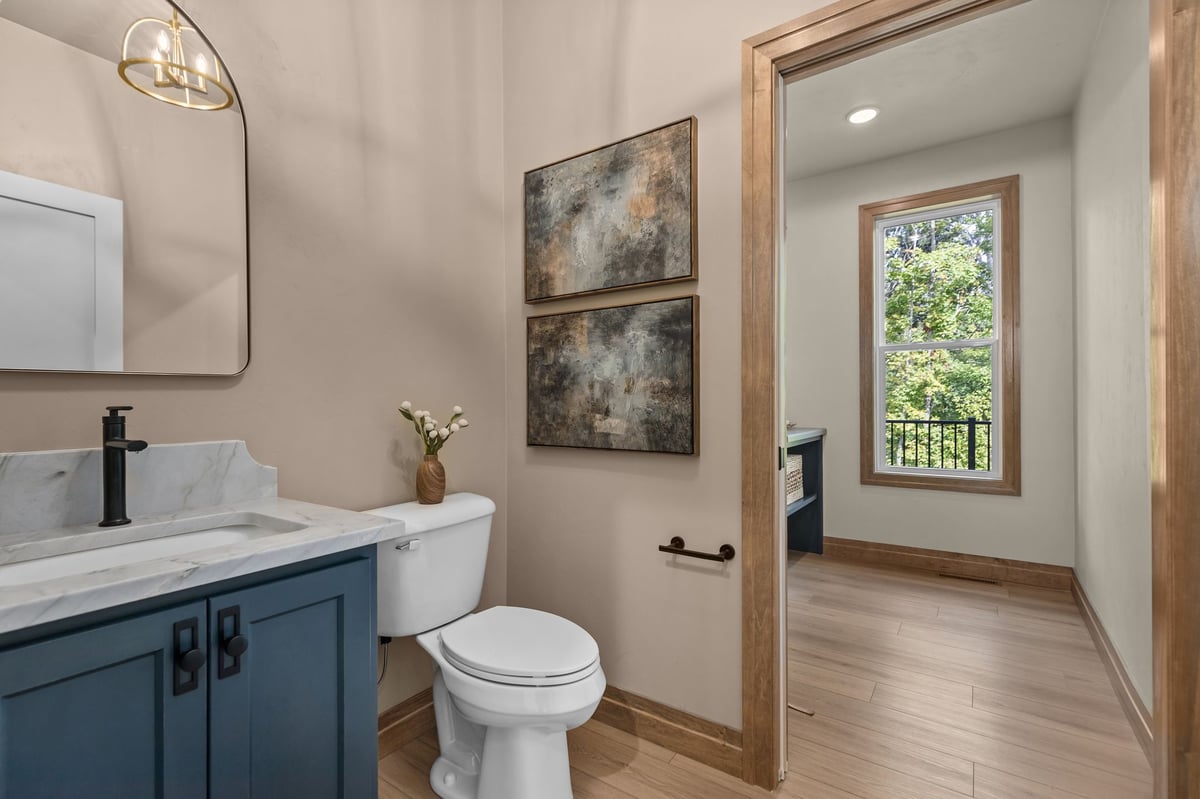 Powder room with blue vanity, marble countertop and black fixtures in a Northeast Wisconsin home