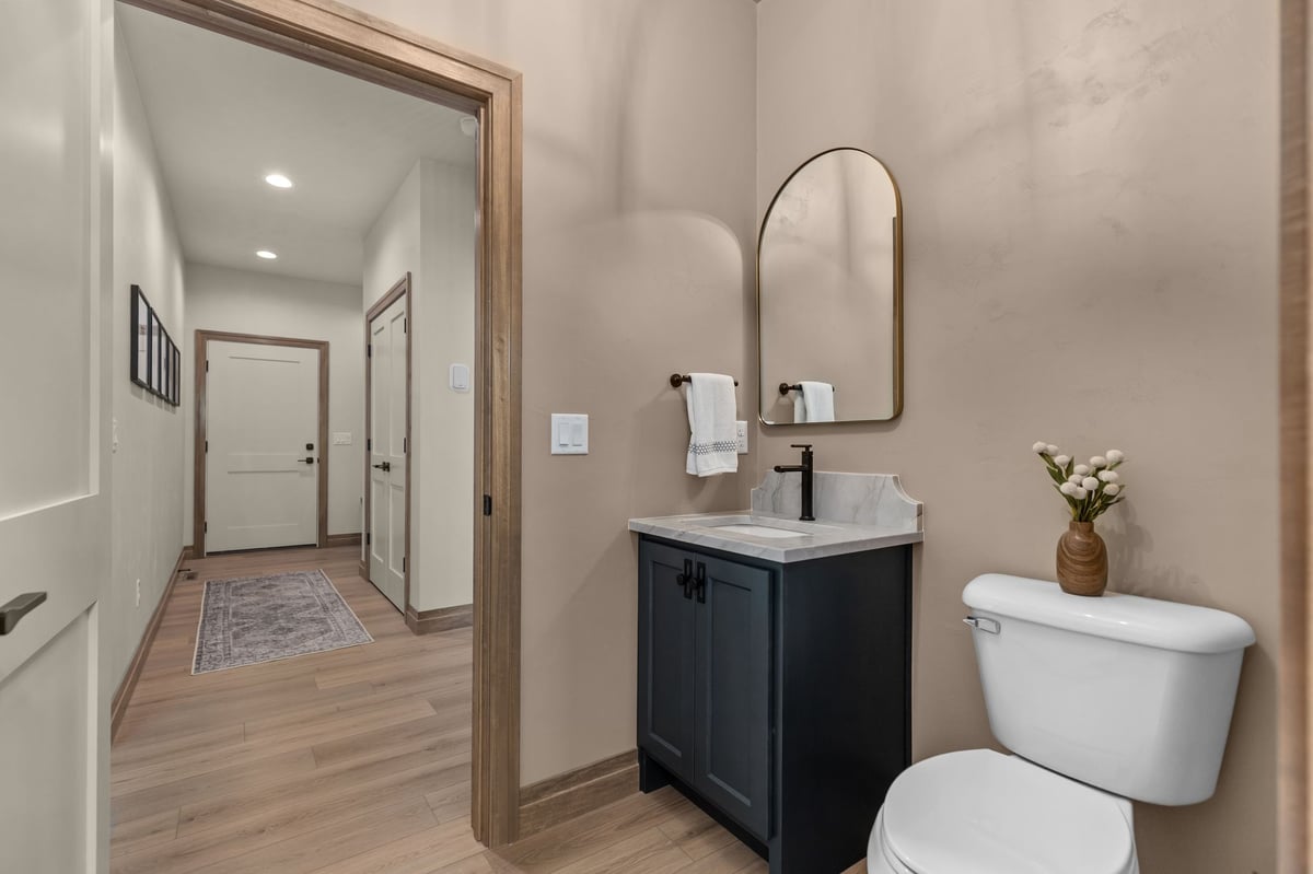Powder room with dark vanity, arched mirror and wood trim in a Northeast Wisconsin home