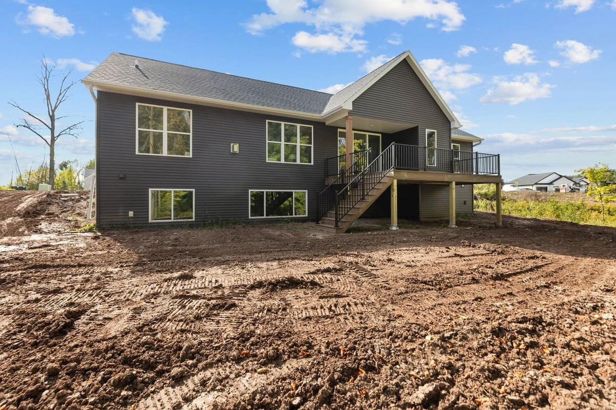 Rear exterior of a Northeast Wisconsin home with dark siding, raised deck and stairs
