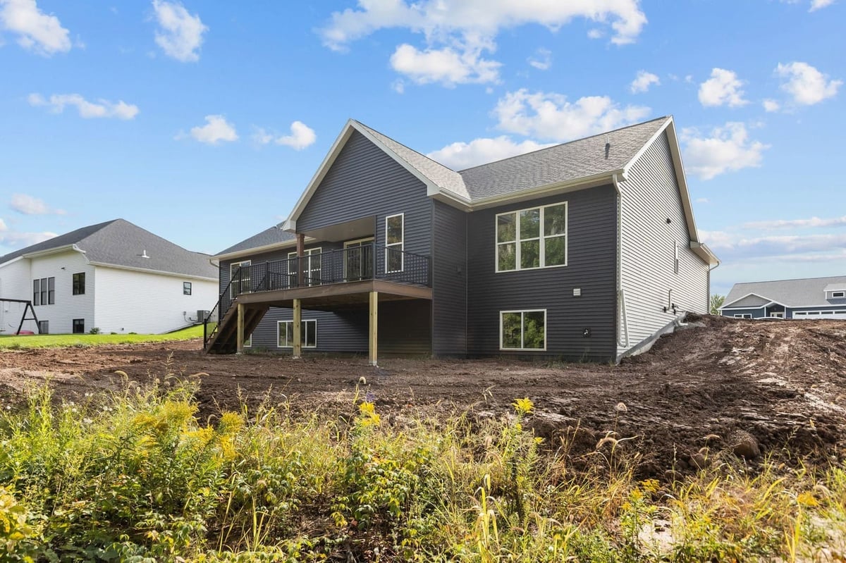 Rear view of a Northeast Wisconsin home with dark siding, raised deck and walkout lower level