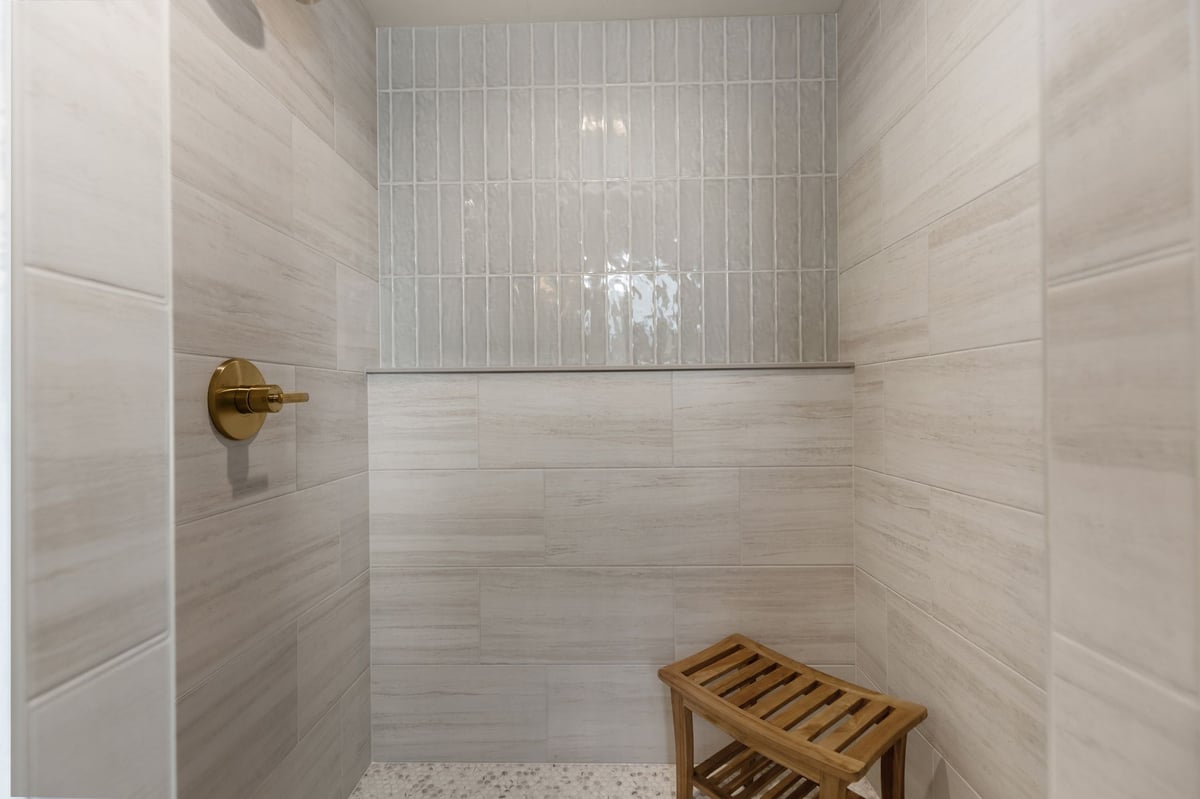 Tiled walk-in shower with brass fixture and built-in ledge in a Northeast Wisconsin home
