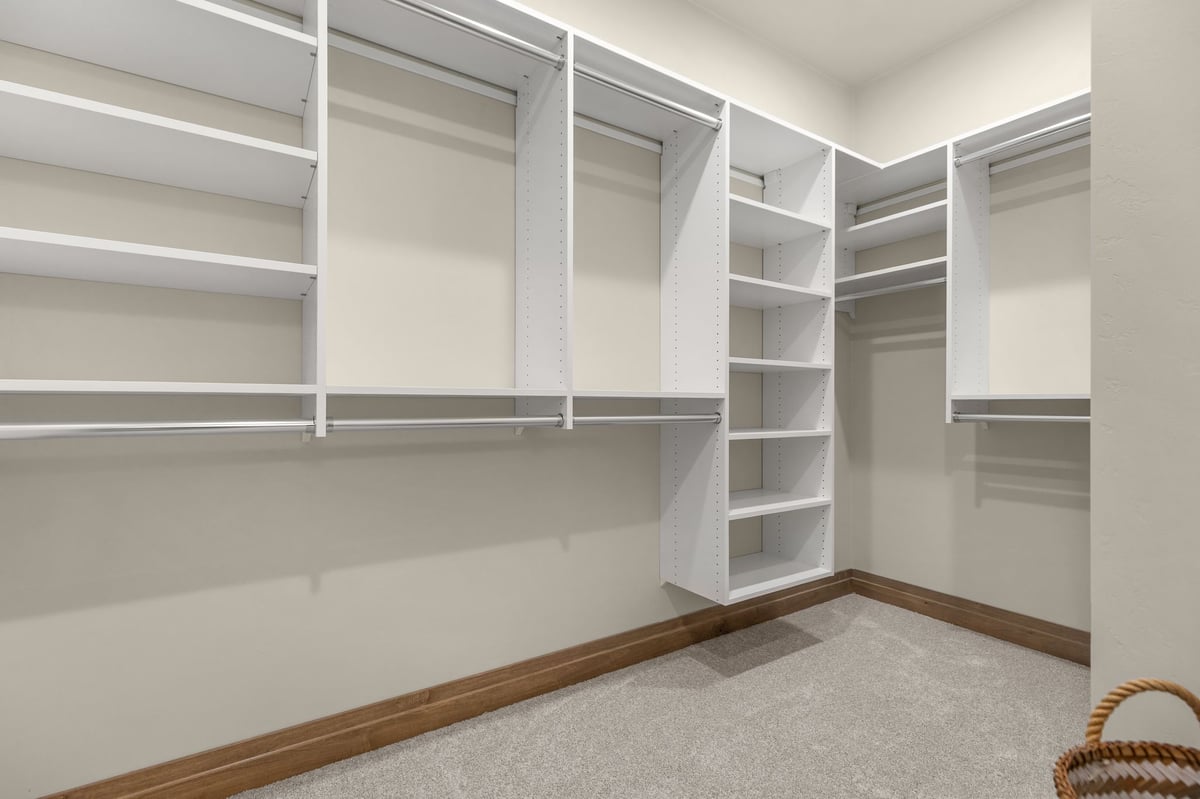 Walk-in closet with white shelving and hanging rods in a Northeast Wisconsin home
