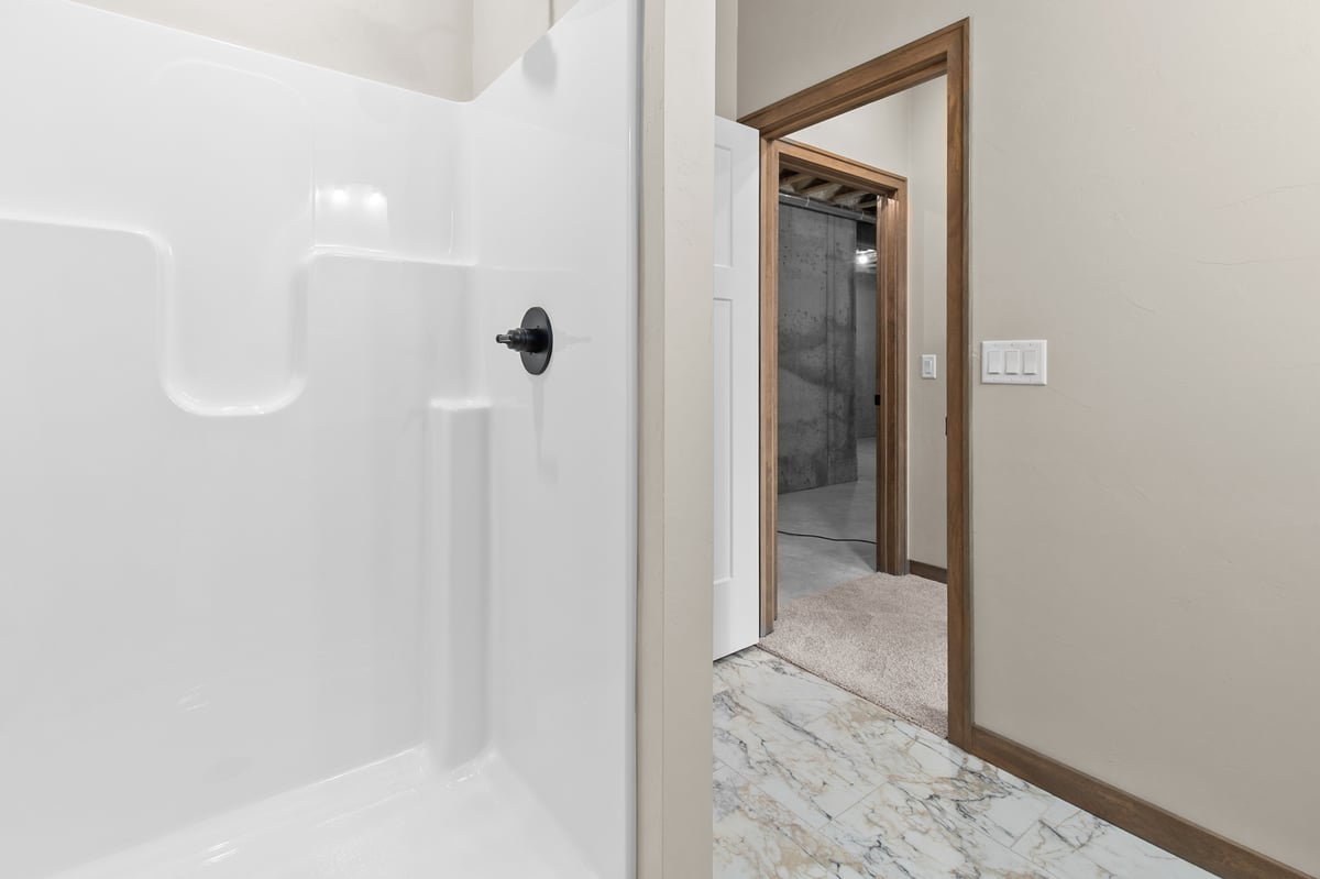 Appleton, WI bathroom with white shower surround, marble-look flooring, and doorway leading to a tiled shower area