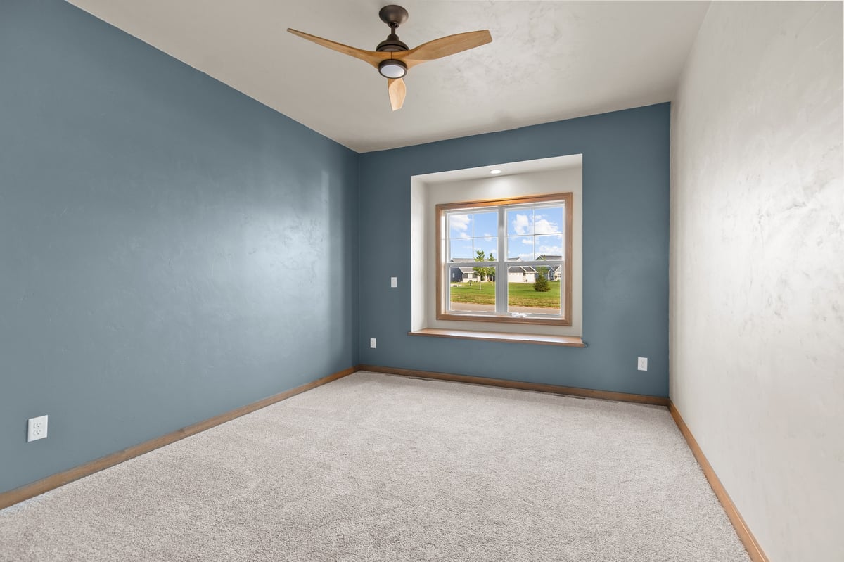 Appleton, WI bedroom with blue accent wall, carpet flooring, ceiling fan, and window with natural light