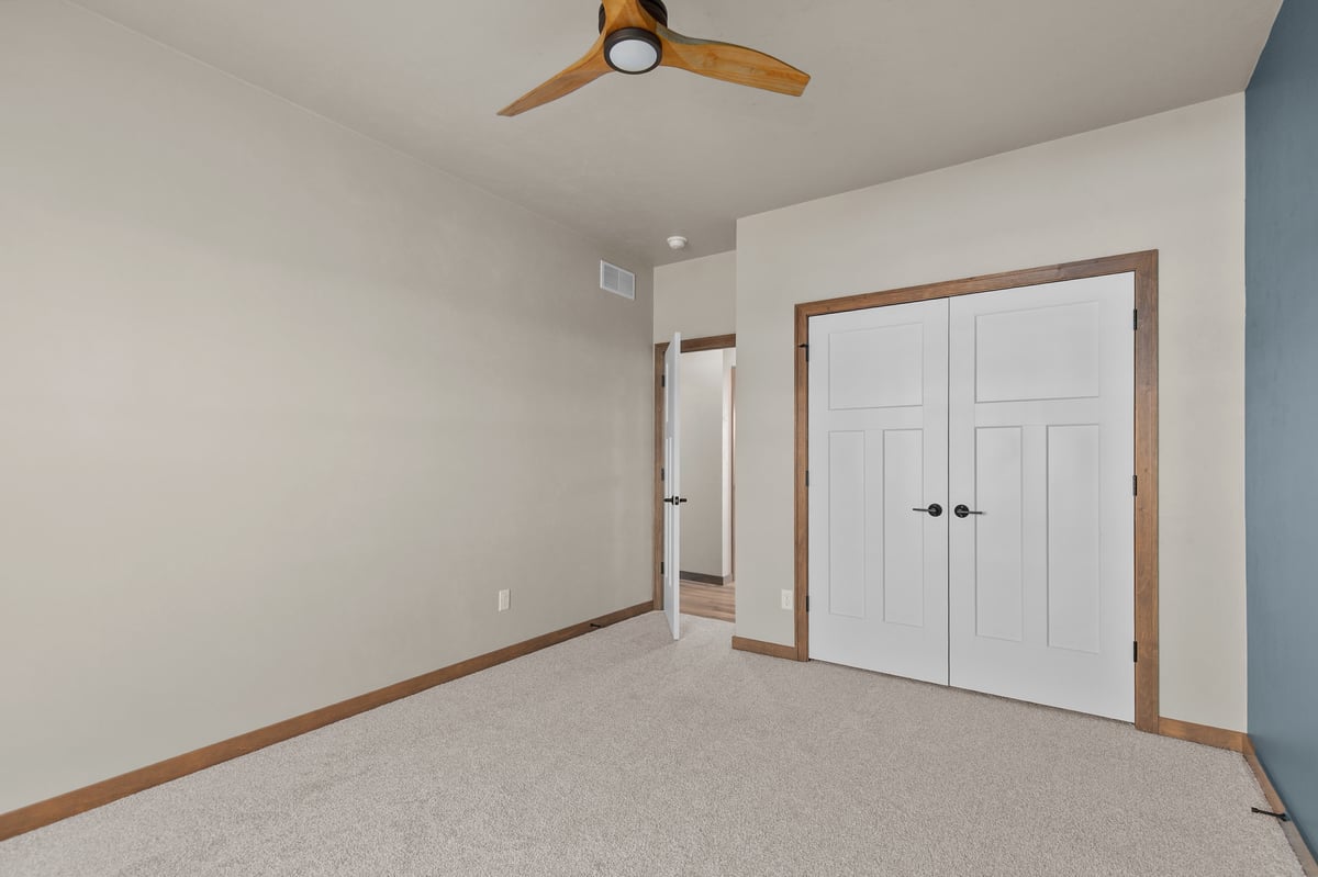 Appleton, WI bedroom with carpet, ceiling fan, double closet doors, and neutral walls with wood trim