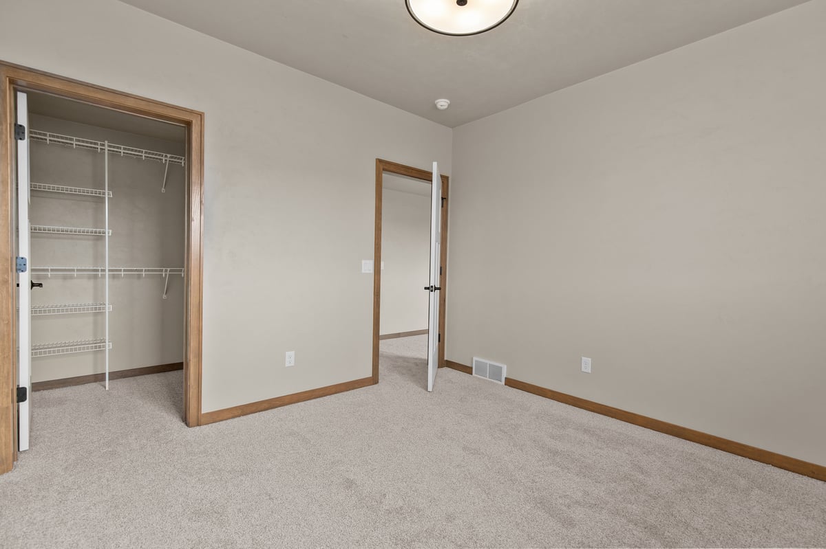 Appleton, WI bedroom with carpet, closet with shelving, neutral walls, and doorway leading to hallway