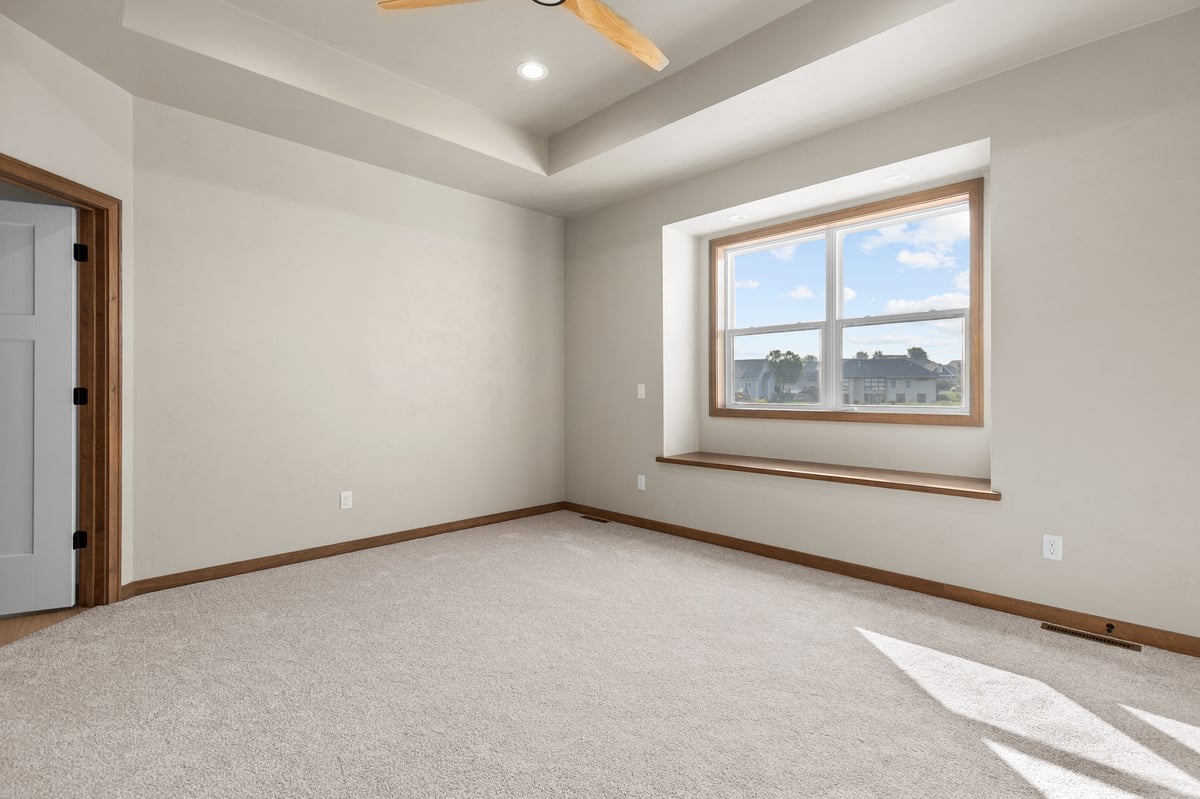 Appleton, WI bedroom with carpet, tray ceiling, large window with bench ledge, and natural light in a neutral-toned space