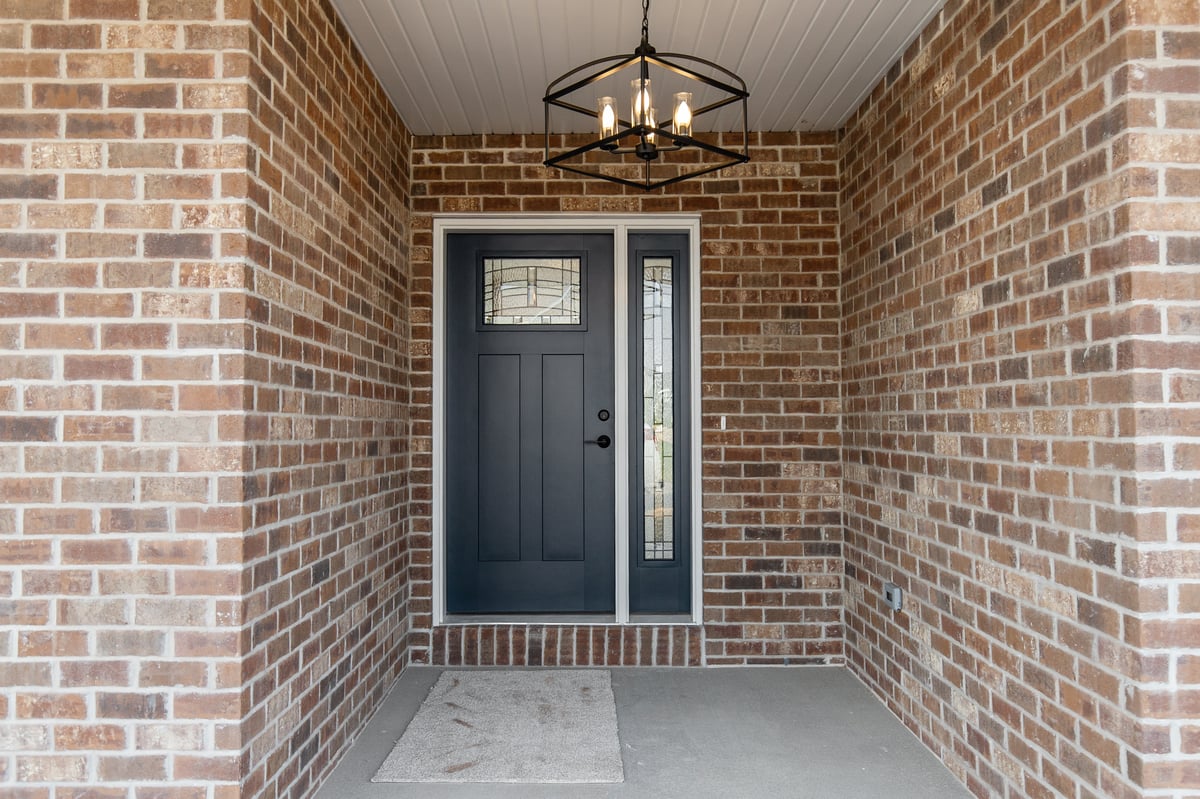 Appleton, WI covered entry with brick walls, dark front door with glass panel, and modern chandelier lighting