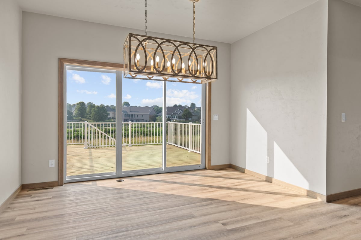 Appleton, WI dining area with large sliding glass door, deck access, modern chandelier, and natural light over wood flooring