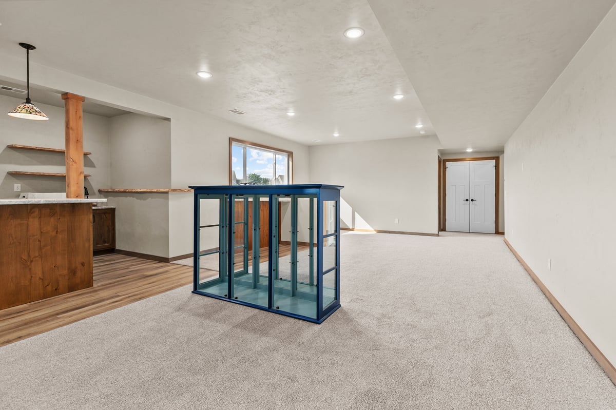 Appleton, WI finished basement with carpet, recessed lighting, open layout, and glass railing overlooking stairwell