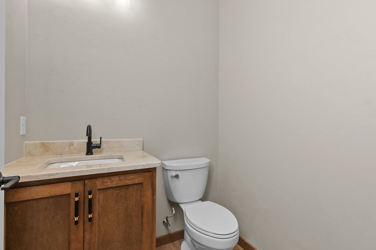 Appleton, WI half bathroom with wood vanity, light countertop, black faucet, and neutral walls