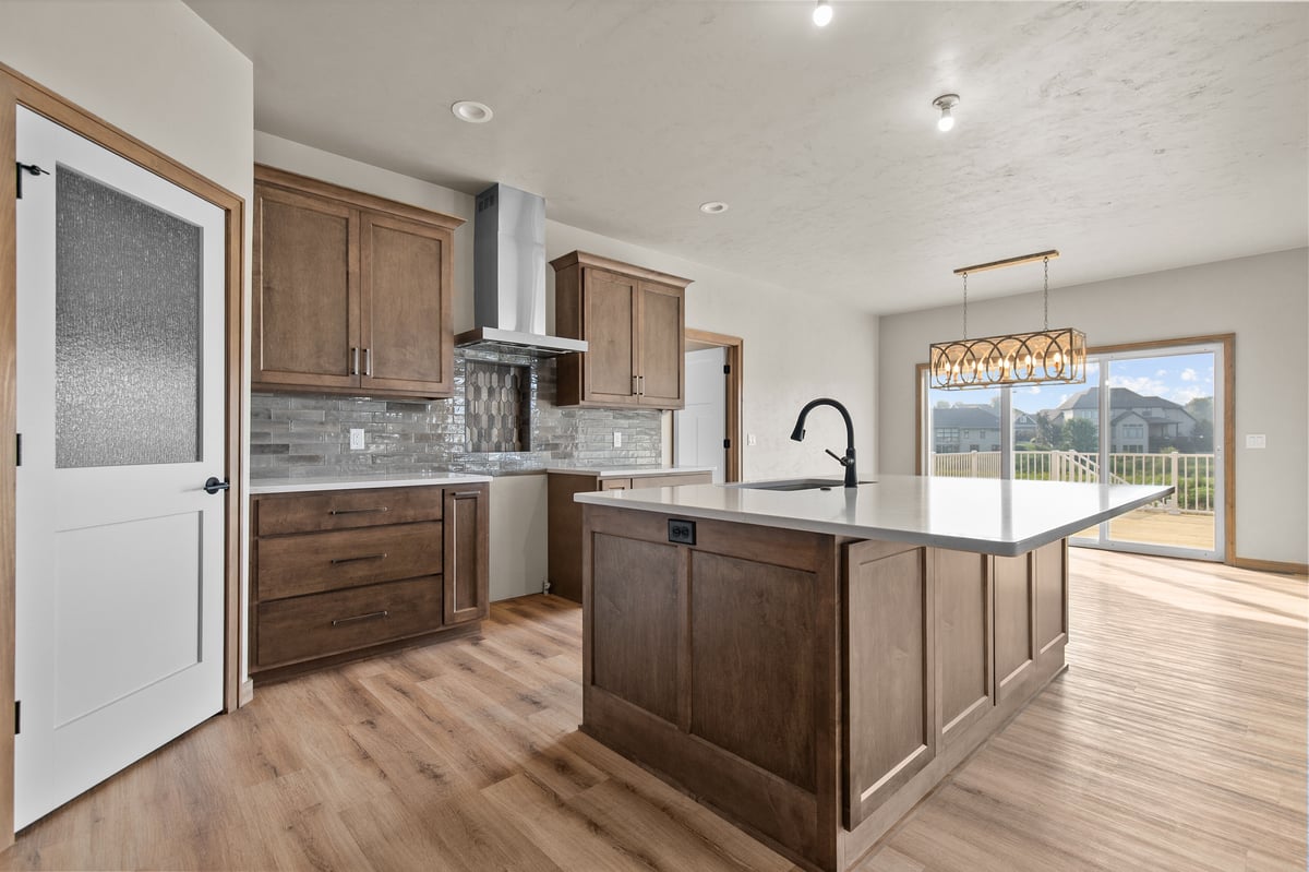 Appleton, WI kitchen with wood cabinets, large island, white countertops, and sliding doors to backyard with natural light