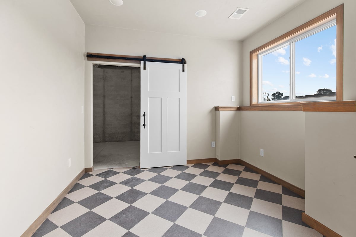 Appleton, WI room with checkered tile floor, sliding barn door, concrete accent space, and window with natural light