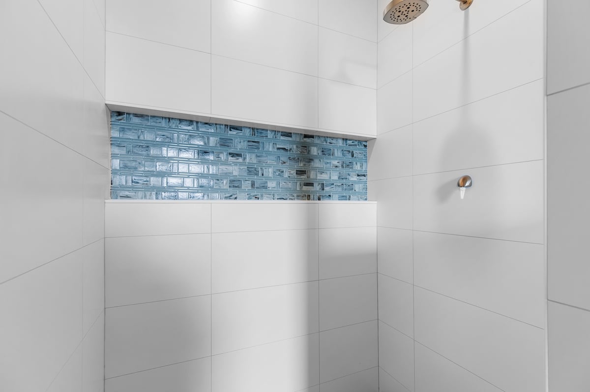Appleton, WI tiled shower with white walls, blue glass accent strip, and modern fixtures in a clean, contemporary bathroom