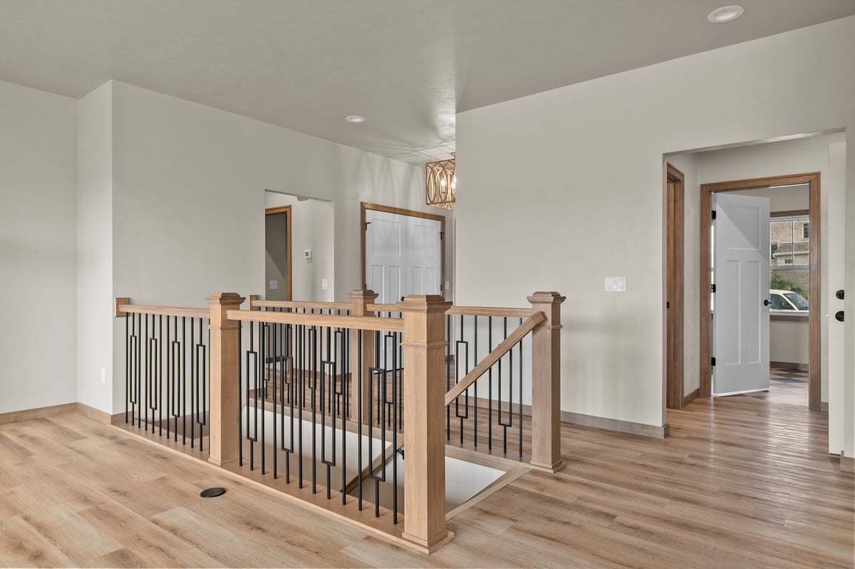 Appleton, WI upper-level landing with wood railing, open stairwell, wood floors, and access to nearby rooms