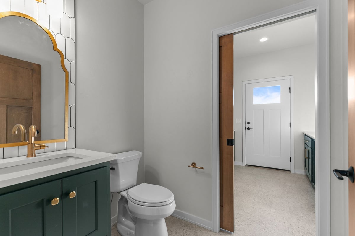 Appleton, WI bathroom with green vanity, gold accents, toilet, and view into hallway and laundry area
