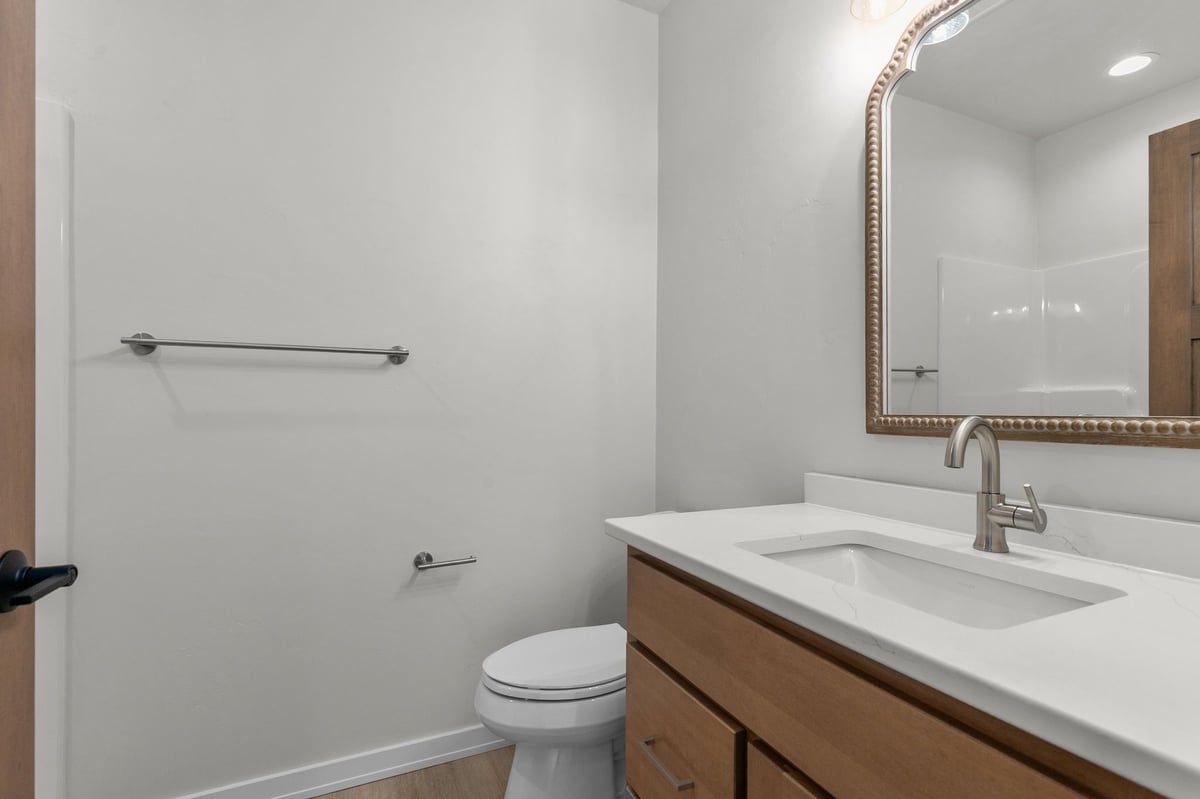Appleton, WI bathroom with wood vanity, white countertop, toilet, and framed mirror
